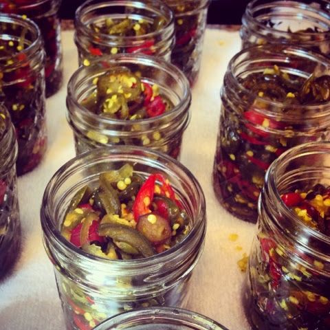 several glass jars filled with pickles and peppers