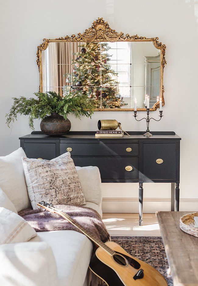 a living room filled with furniture and a christmas tree on top of a table in front of a mirror