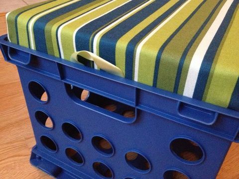 a blue plastic box sitting on top of a wooden floor next to a green and white striped table cloth