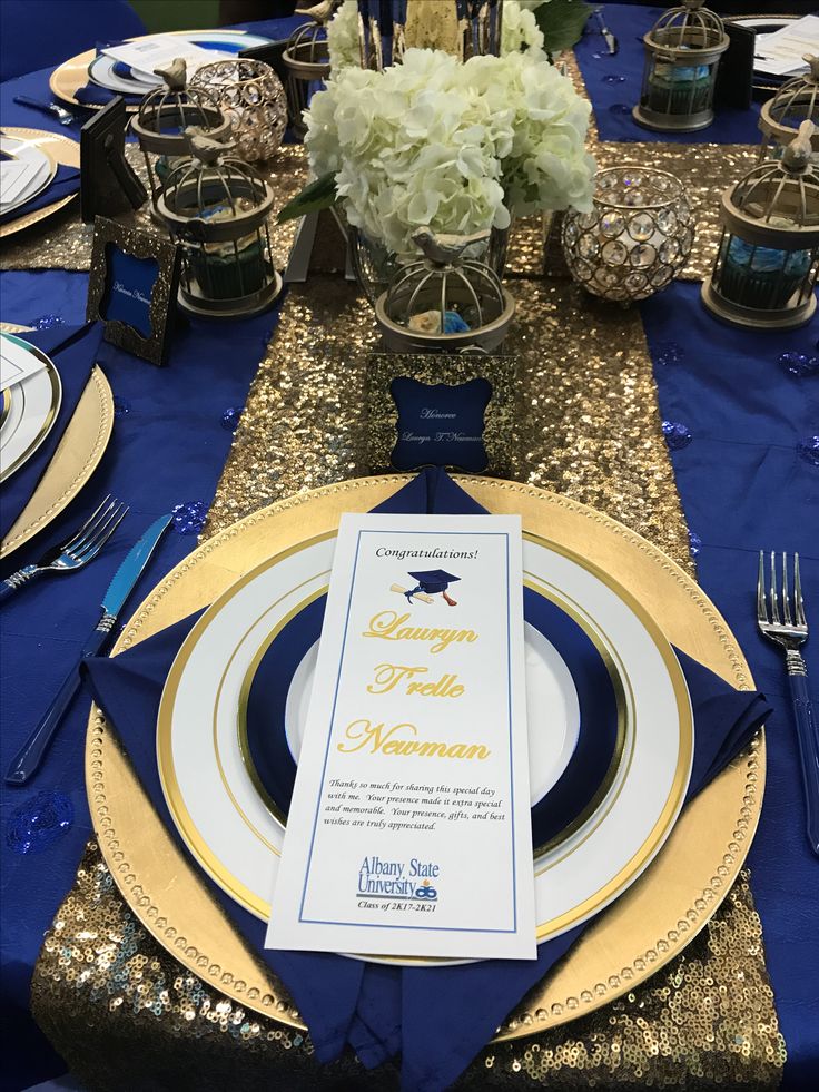 the table is set with blue and gold place settings, silverware, and napkins