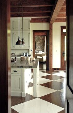 an open door leading to a kitchen with white cabinets and checkered tile flooring