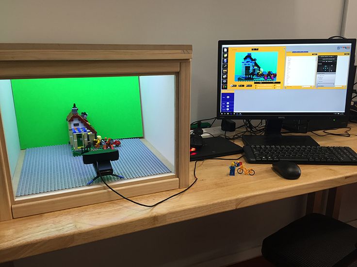 a desk with two computer monitors and a lego house on the monitor, sitting next to each other