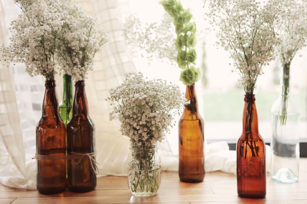 three brown bottles with flowers in them sitting on a table