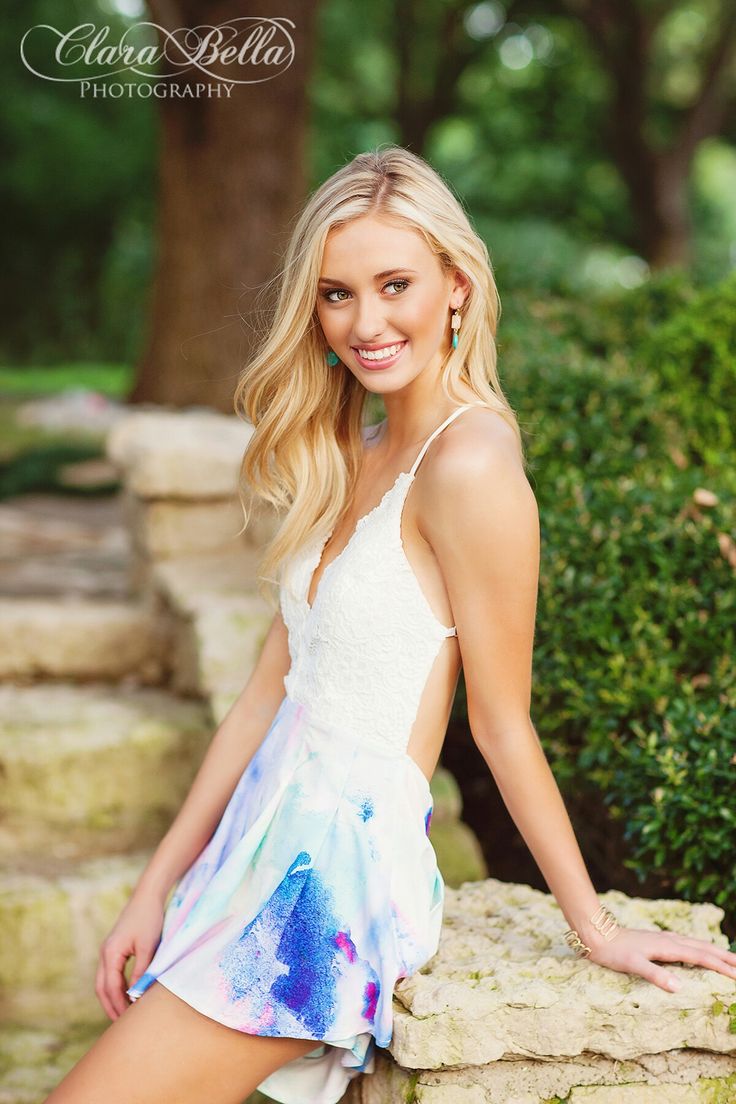 a beautiful blonde woman posing for a photo in a white top and blue tie dye dress