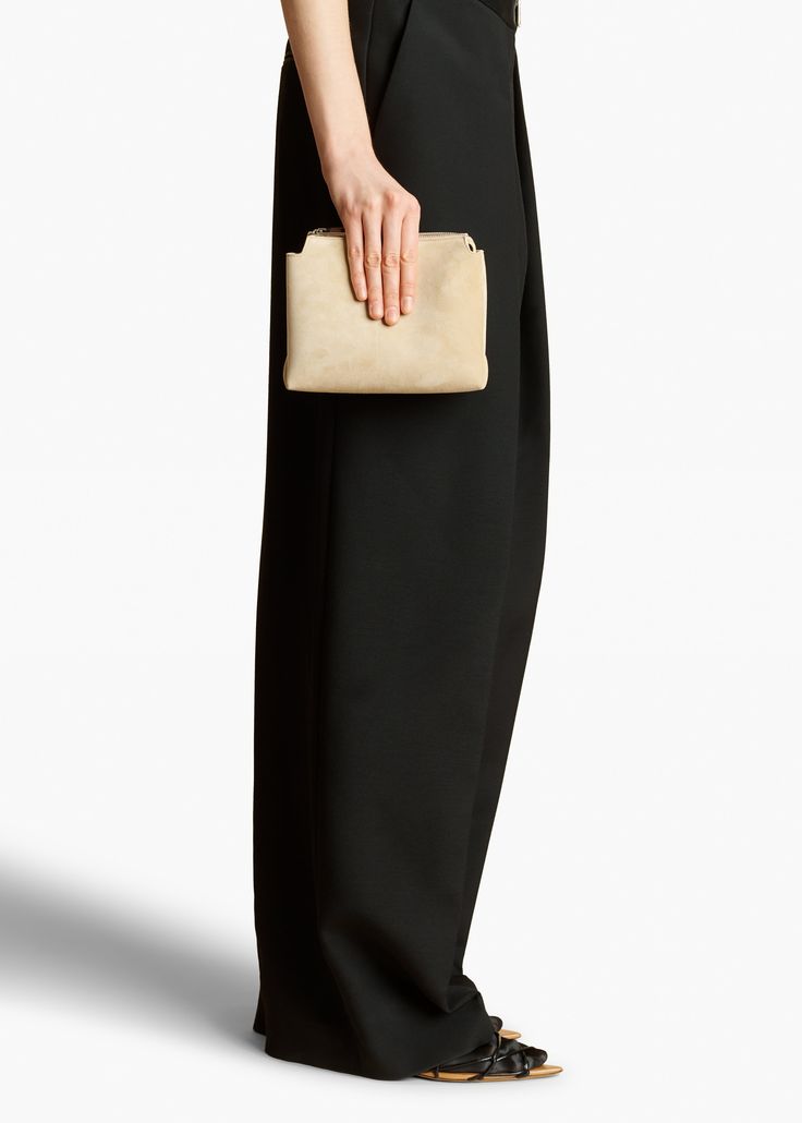 A lightweight pouch shaped by sculptural folds along the sides. The extended zipper closure allows allows for full access to the interior. Luxury Textured Suede Shoulder Bag, Khaite Suede Bag, On-the-go Rectangular Soft Leather Clutch, Luxury Black Textured Leather Clutch, Black Leather-lined Pouch Clutch, Pouch