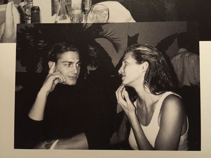 a man and woman sitting next to each other in front of a table with drinks