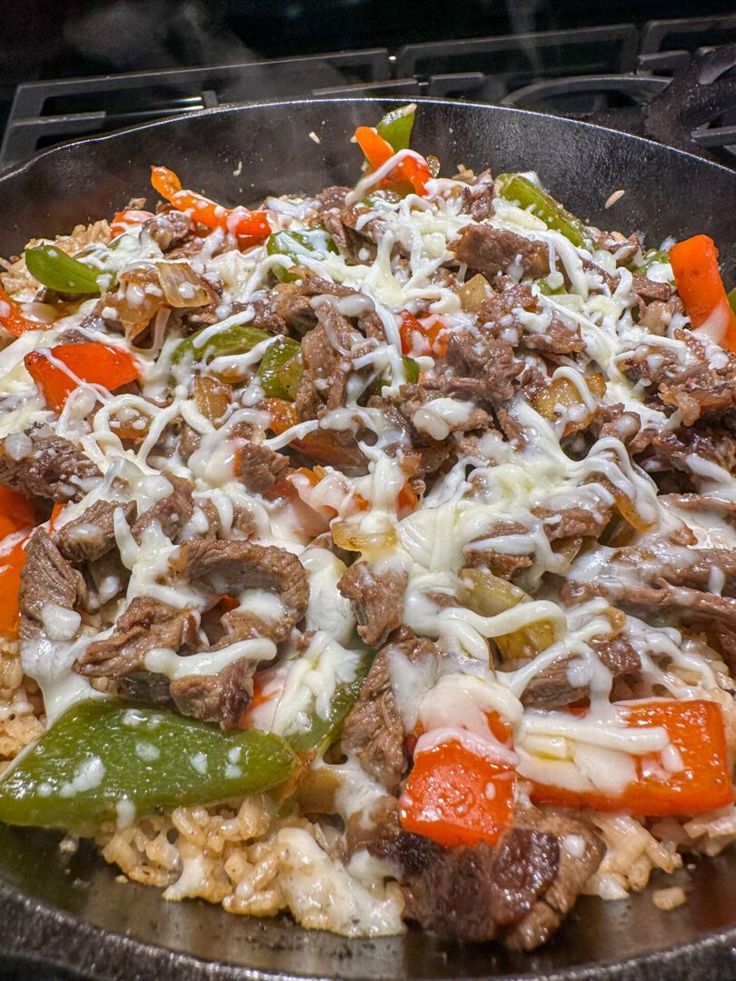 a skillet filled with meat and veggies covered in cheese