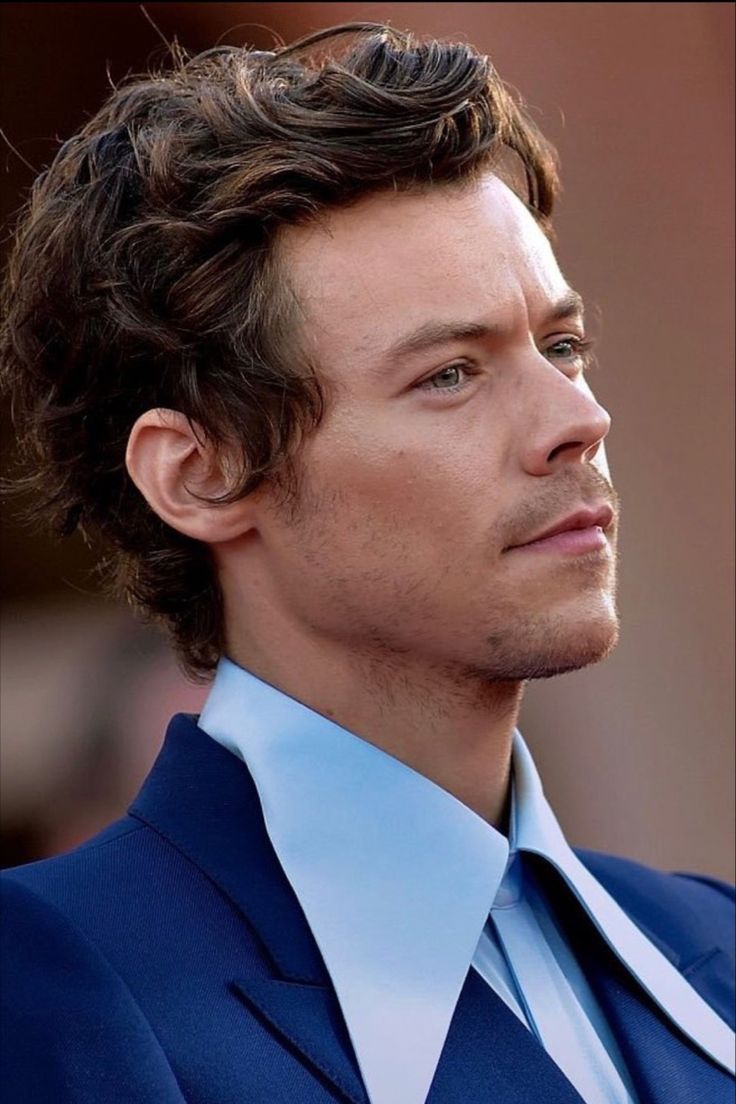 a close up of a person wearing a suit and tie with his hair in the wind