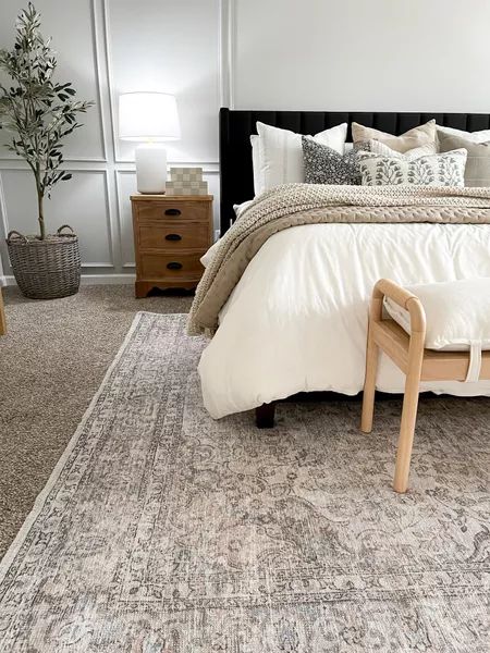 a bedroom with a bed, dresser and rug on the floor in front of it