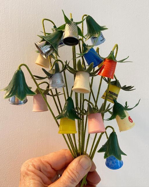 a person holding up a bunch of flowers made out of plastic cups and other items