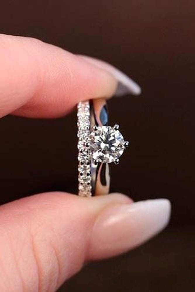 a woman's hand holding an engagement ring with a diamond on the top and side