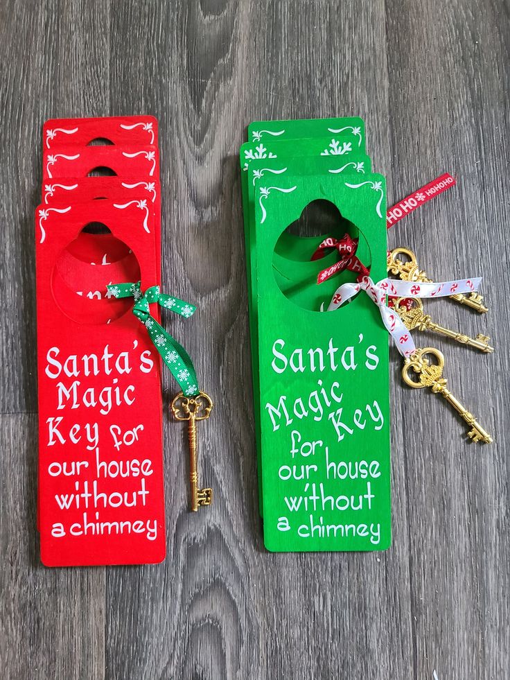 two door hangers with keys attached to them on a wooden floor, one has a santa's key and the other is a house without a chimney