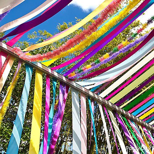 colorful streamers are hanging from the side of a palm tree in front of a blue sky