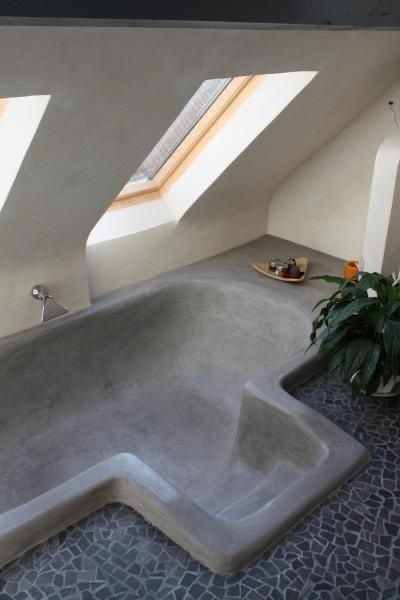 an indoor hot tub in the middle of a room with skylights above it and a potted plant next to it