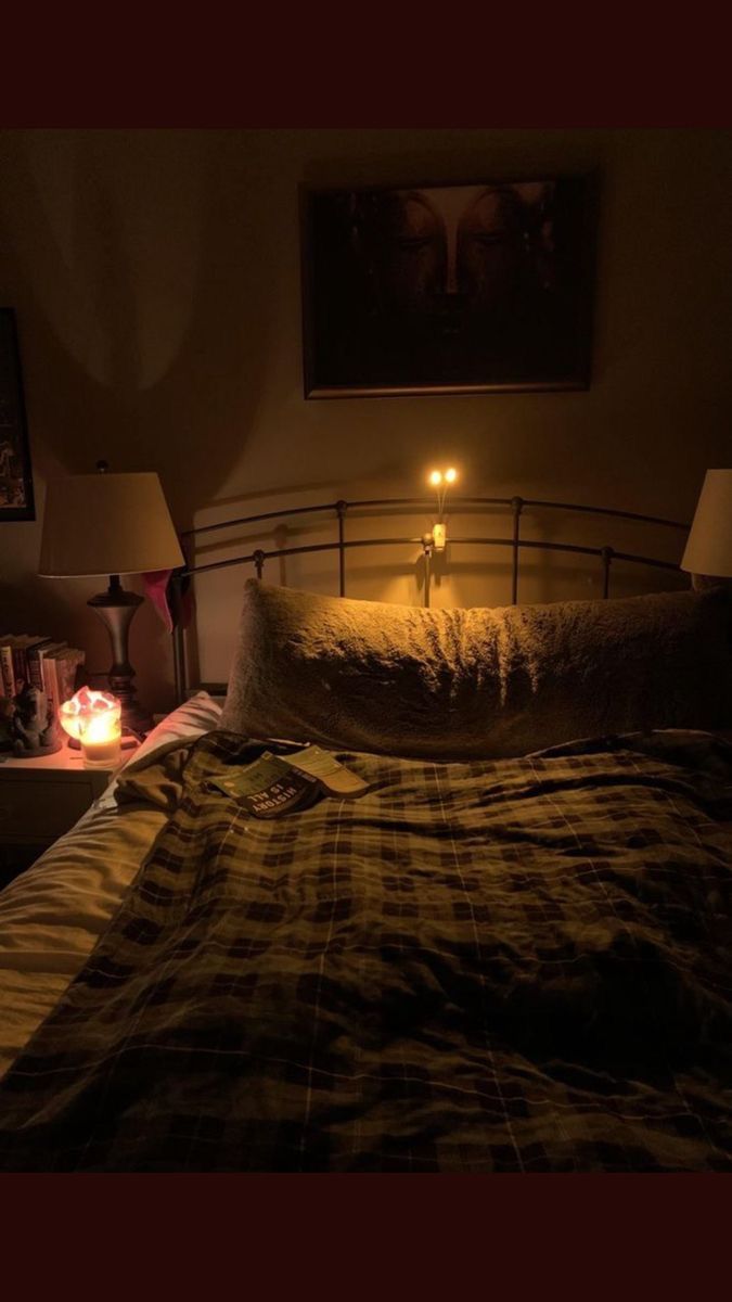 a bed with two lamps on either side of it and a night stand in the background