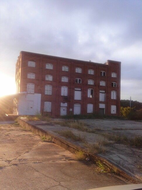 an old brick building sitting on the side of a road next to a parking lot