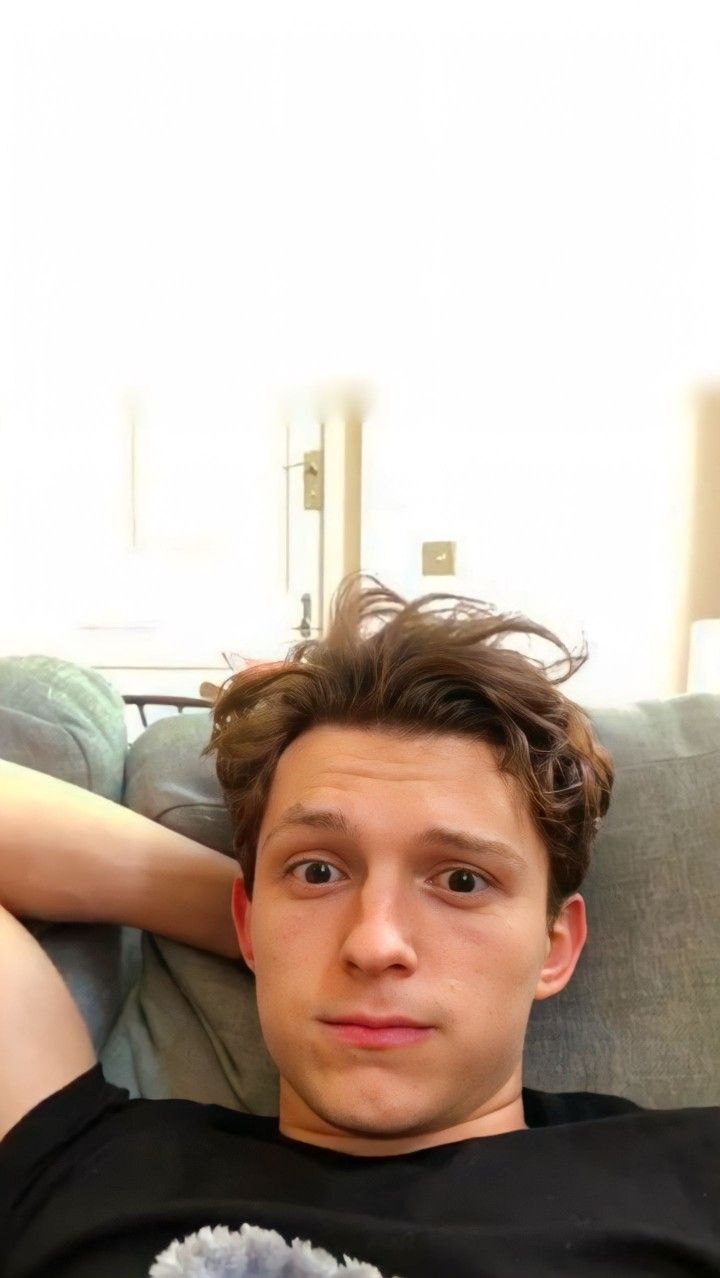 a man sitting on top of a couch holding a stuffed animal next to his head