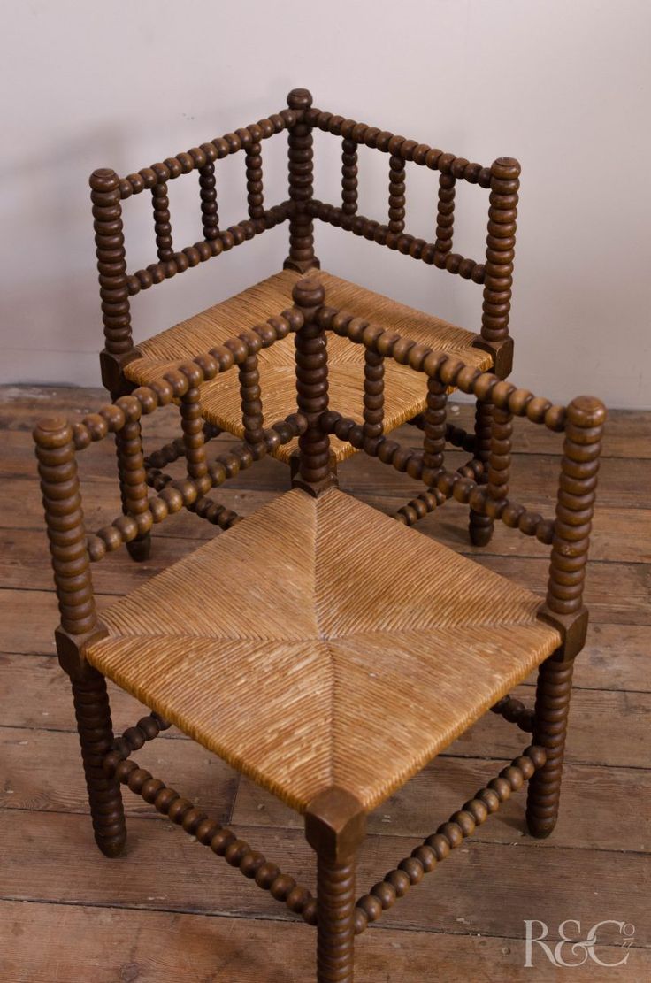 two chairs made out of sticks and wood on a wooden floor with a wall in the background