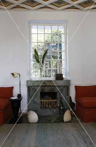 a living room with two red chairs and a fire place in the middle of it