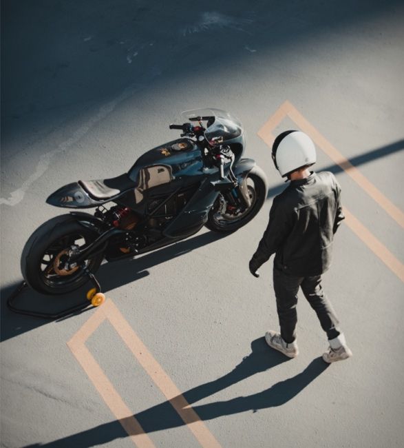 a person standing next to a motorcycle in a parking lot with no one on it