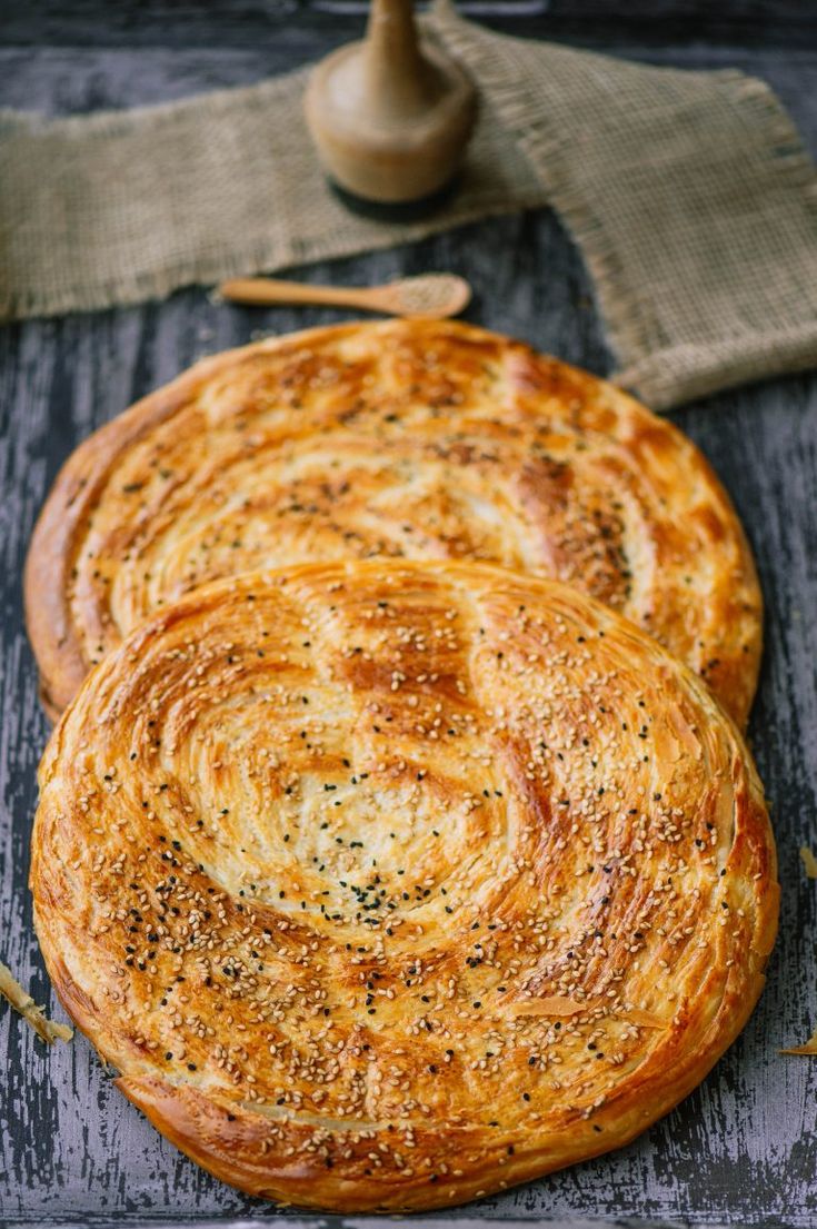 three round breads sitting on top of a wooden table