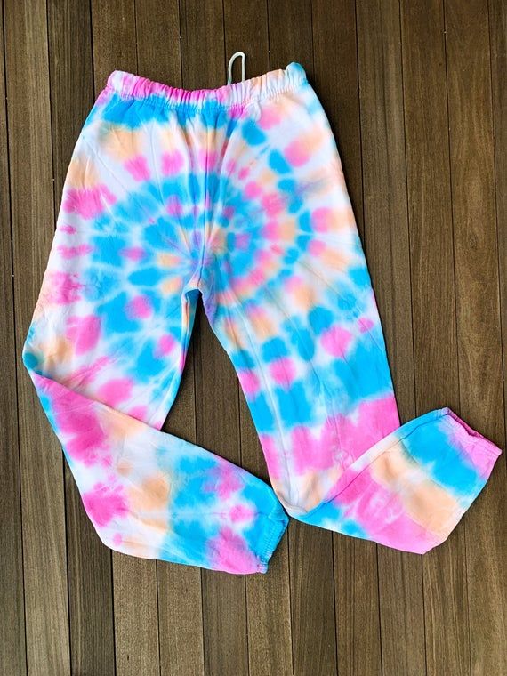 a pair of pink, blue and yellow tie - dyed sweatpants sitting on top of a wooden floor