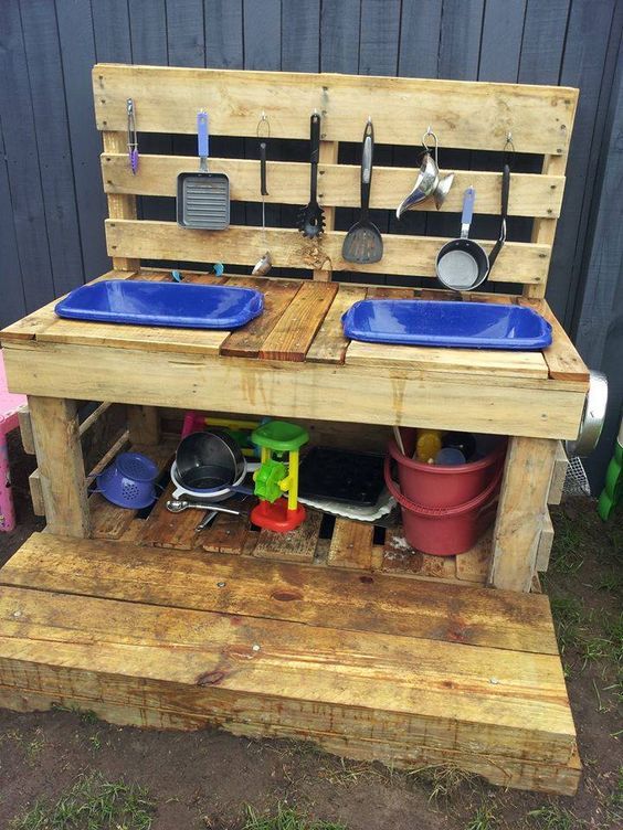 an outdoor kitchen made out of pallets with blue bowls and pans on it