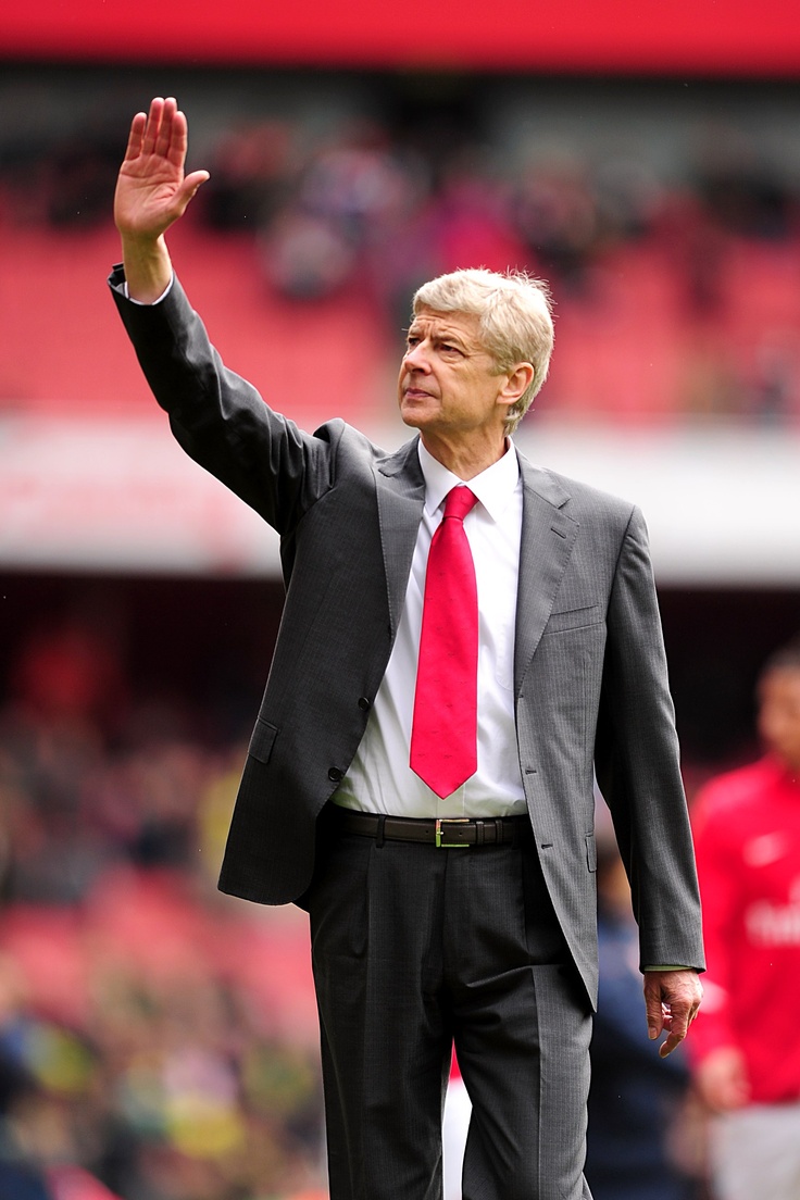 an older man in a suit and tie waves to the crowd at a soccer game