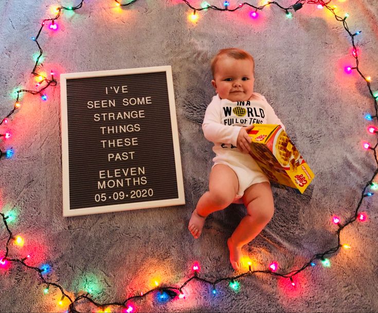 a baby is laying next to a sign that says i've seen some strange things these past eleven months