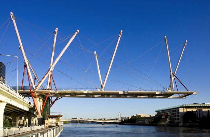 a bridge that is over some water with buildings in the back ground and blue sky