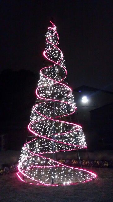 a lighted christmas tree in the middle of a field at night with lights on it