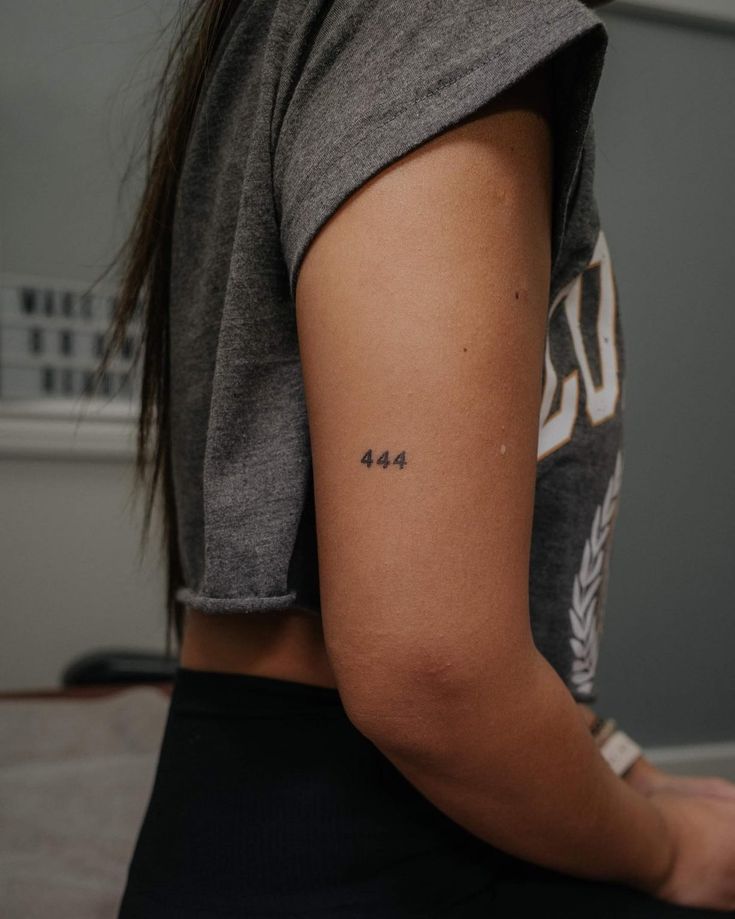 a woman with a small tattoo on her left arm and the number forty four behind her