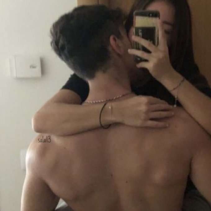 a man and woman taking a selfie in front of a mirror with their arms around each other