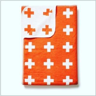 an orange and white blanket with crosses on the front is folded in two different directions