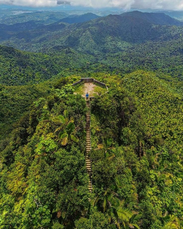 an aerial view of the top of a mountain with stairs leading up to it and lush green mountains in the background