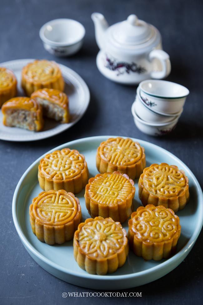 small moon cakes on a plate with tea cups and saucers in the back ground