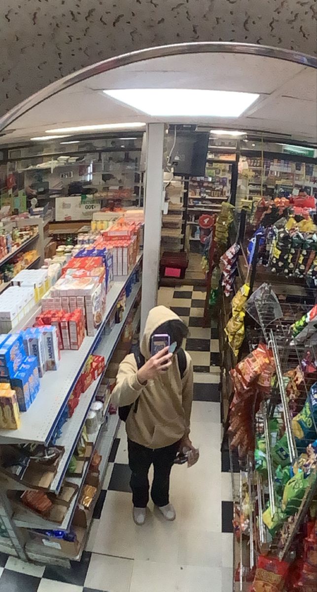 a woman is taking a selfie in the grocery section of a store while looking at her phone