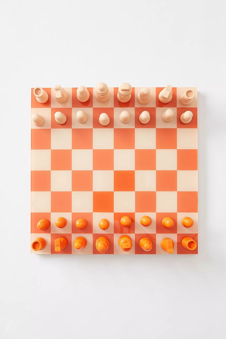 an orange and white checkerboard board with chess pieces on the top, in front of a white background