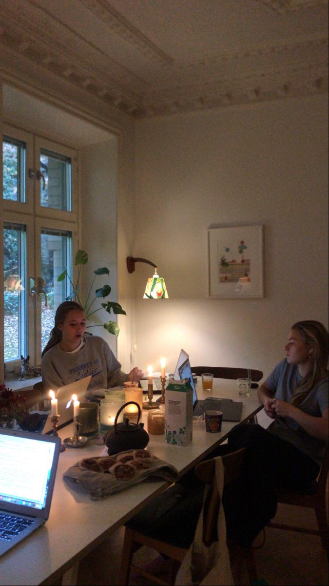 two people sitting at a table with laptops and candles in front of their faces