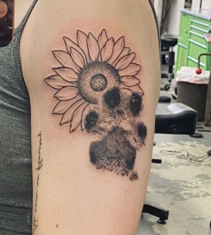 a woman's arm with a sunflower and dog paw tattoo on the left shoulder