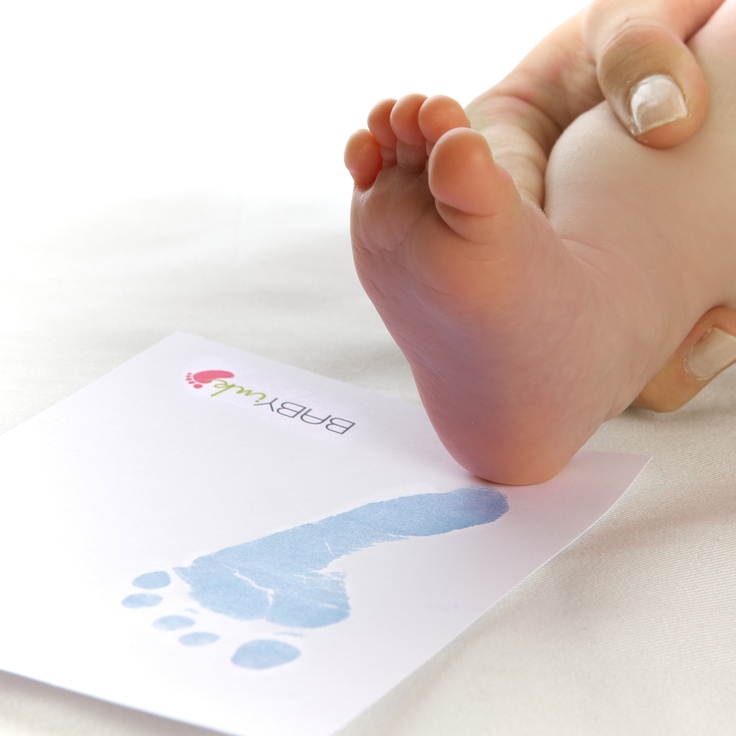 a baby's foot is being held up to the ground by a hand print