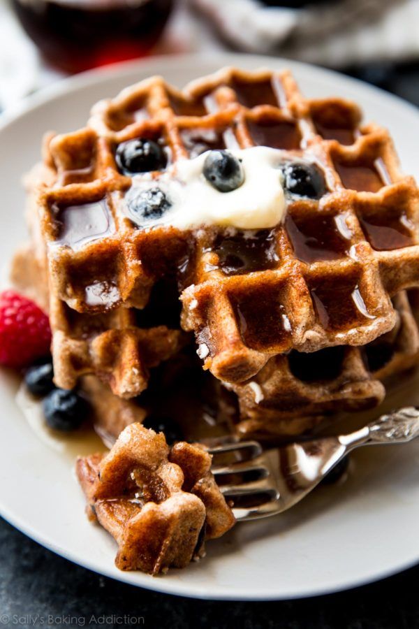 a white plate topped with waffles covered in syrup and blueberries