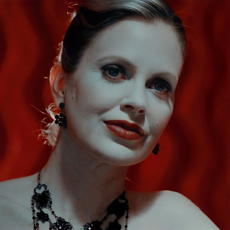 a woman with makeup and jewelry on her face is posing for a photo in front of a red background