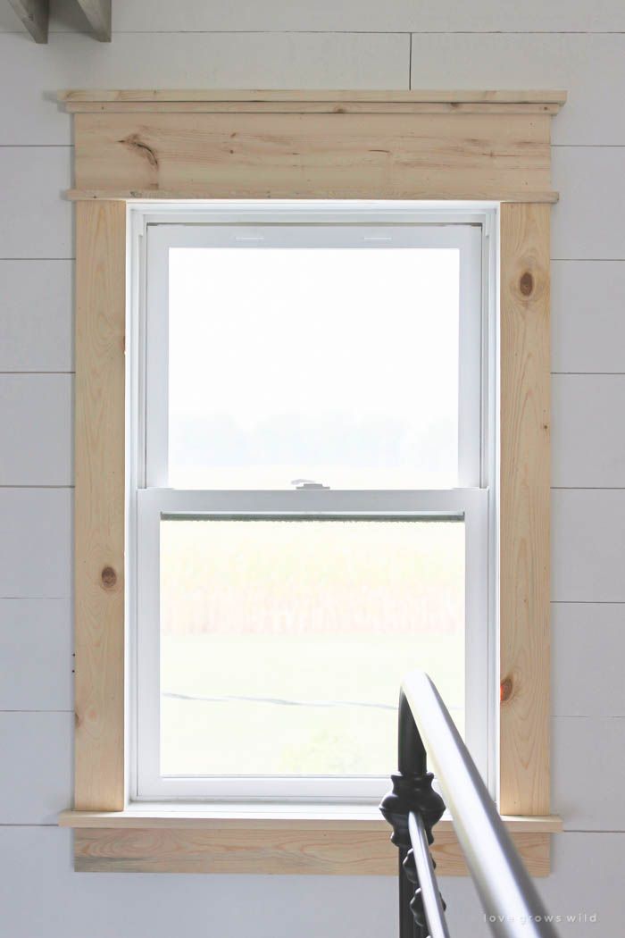 a window in the corner of a room with white walls and wood trimmings