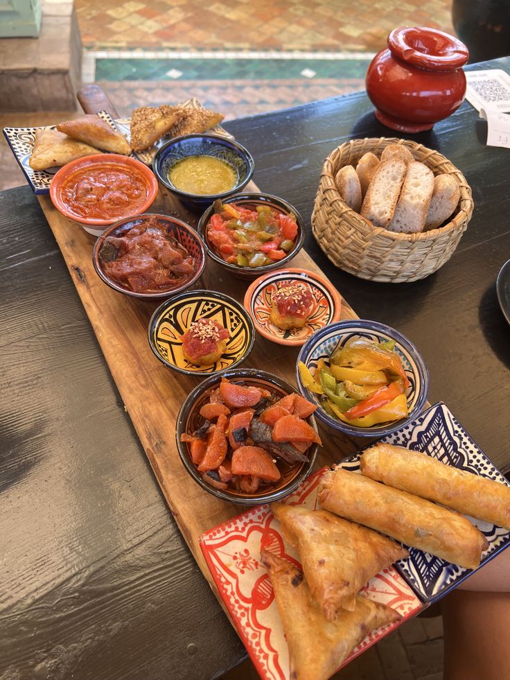 a wooden table topped with lots of different types of food and dipping sauces on top of it