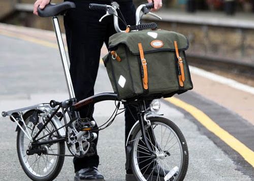 a person standing next to a bike with a bag on the front and back rack