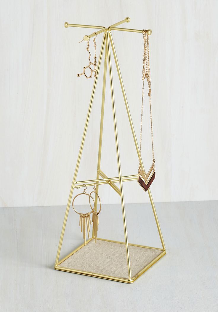 a gold jewelry stand with two necklaces and a ring on the bottom, hanging from it's sides