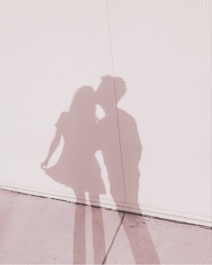 the shadow of a person standing next to a wall with a skateboard on it