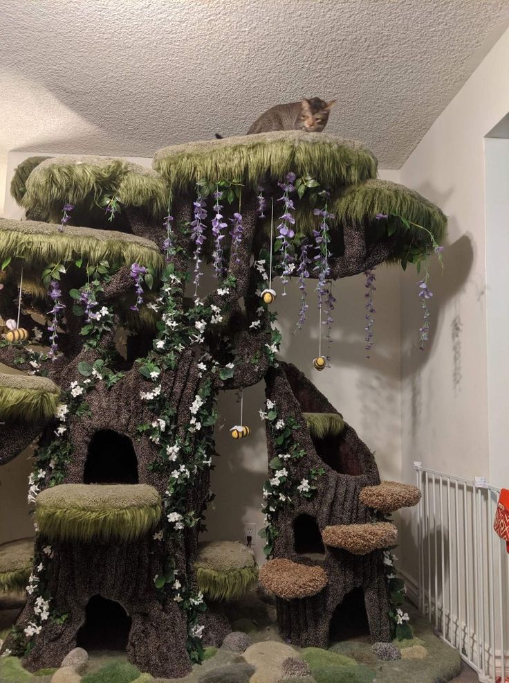 a cat sitting on top of a tree house made out of fake grass and flowers