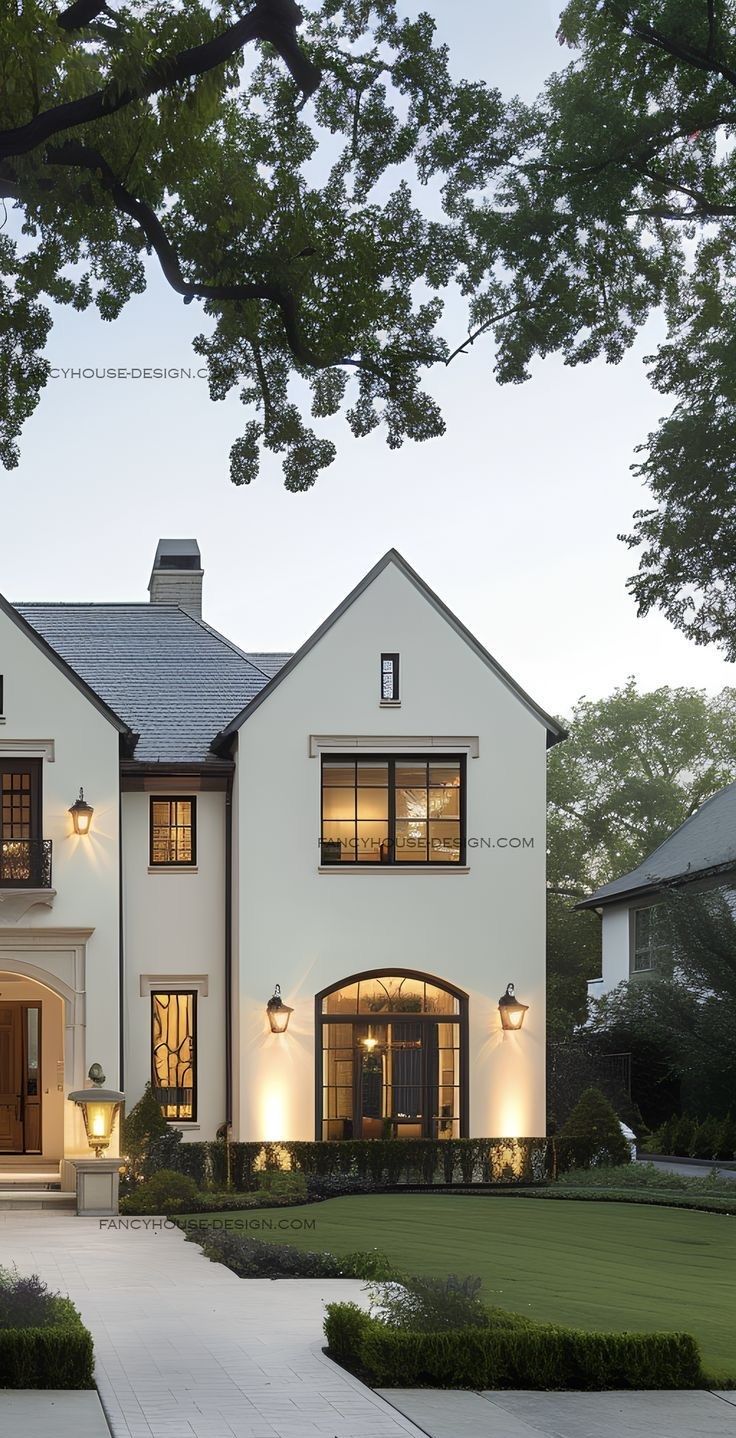 a large white house with lots of windows and lights on it's front door